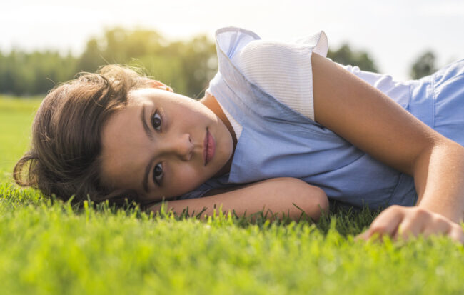 little-girl-looking-camera-while-staying-grass